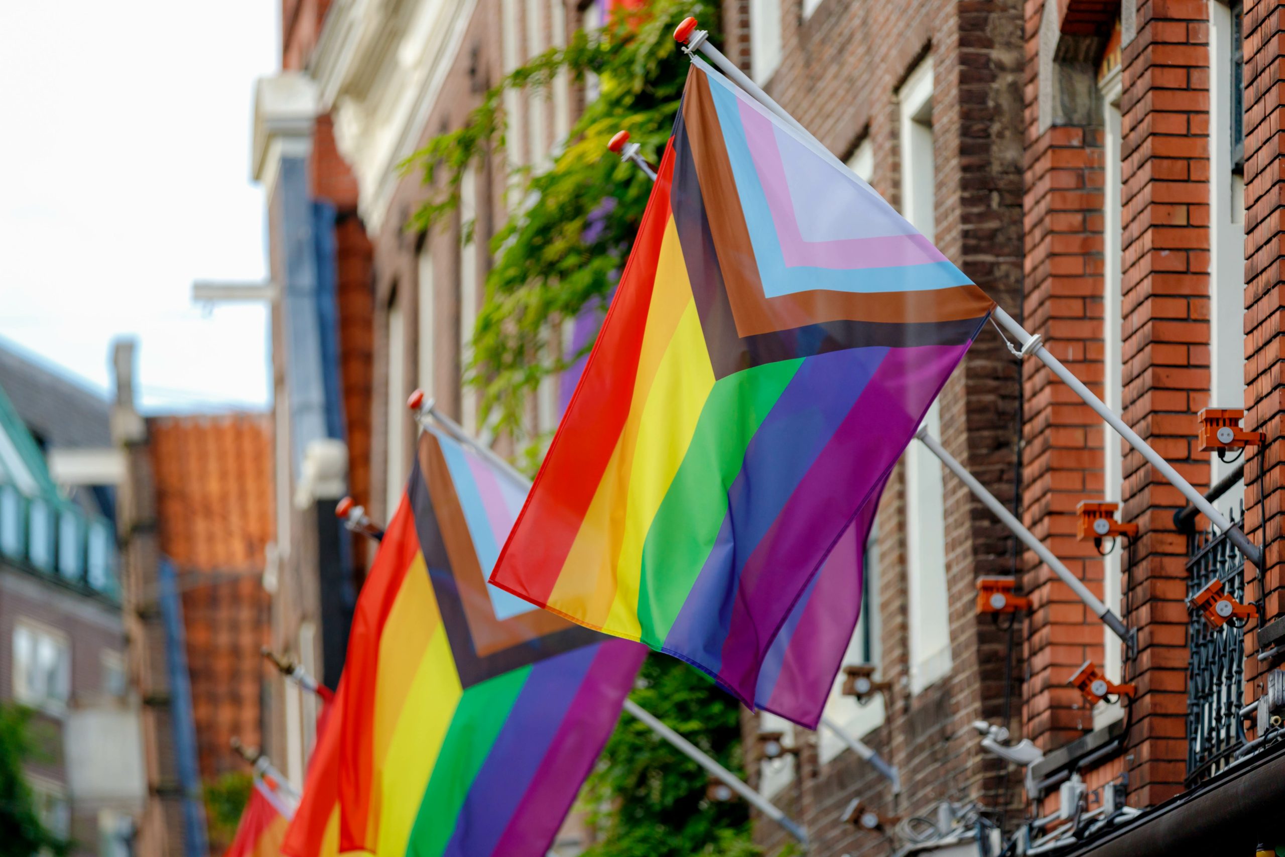 Progress Pride flags mounted on a brick building in Tacoma